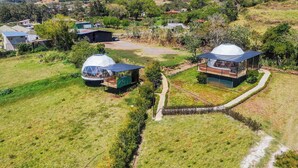A rural area with modern dome-shaped buildings, a clear sky, and a hilly landscape in the background. - Tocuma Glamping (San Rafael)