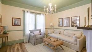 A living room with two sofas, a coffee table, a chandelier, and framed pictures on the wall. - Oliver Twist Cottage - Walk to Downtown - Hot Tub & Grill-Cozy Charm (Chattanooga)