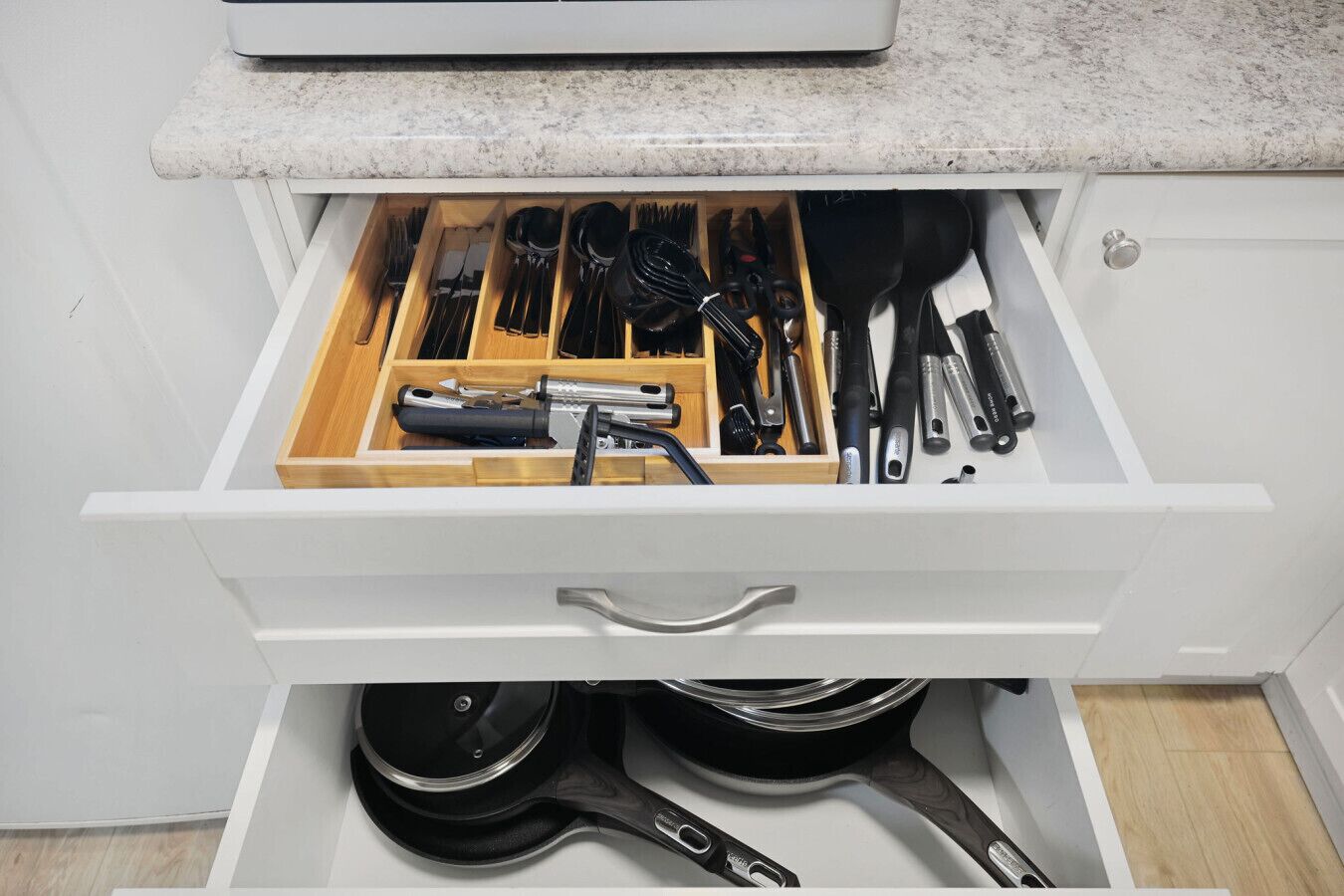 A kitchen drawer with utensils and cookware.