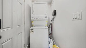 A laundry room with a stacked washer and dryer, a power outlet, and a door. - 2 BR 1 Bath Apt with Parking | Close to Amenities (Oshawa)