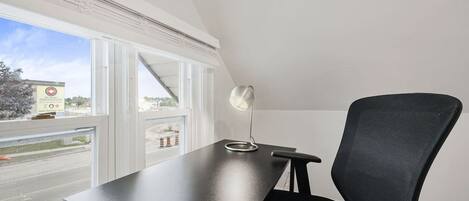 Un espacio de oficina moderno con escritorio, silla y ventana con vistas al exterior.