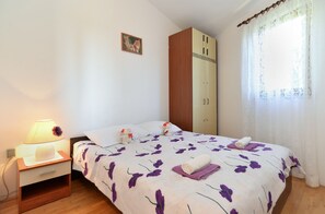 A bedroom with a bed, a nightstand, a lamp, a wardrobe, and a window with curtains. - Apartment 2412/168845 (Istria - Premantura), 1000m from the beach (Premantura)