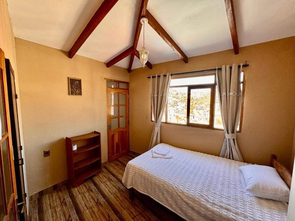 Un dormitorio con cama de madera, un escritorio y una ventana con cortinas.
