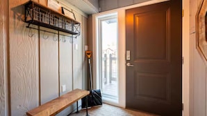 Un couloir avec un banc, une porte et un porte-chaussures.