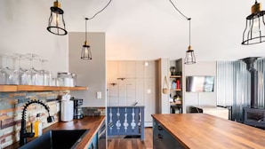 Une cuisine moderne avec des plans de travail en bois, des luminaires suspendus et une cuisinière intégrée.