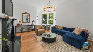 Een moderne woonkamer met een blauwe bank, een ronde salontafel en een open haard.