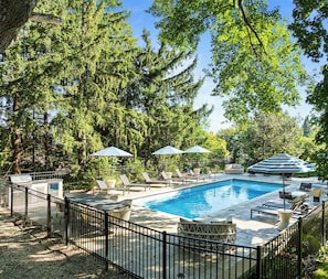 A pool area with lounge chairs, umbrellas, and a fenced pool.