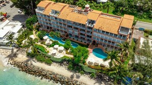 Ein mehrstöckiges Hotel mit Poolbereich, Strandlage und Meerblick.