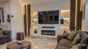 Una sala de estar moderna con un televisor de pantalla plana, una chimenea y un área de descanso confortable.