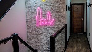 Una escalera con un letrero de neón que dice "IMANC" y un símbolo de abeja encima.