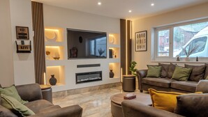 Una sala de estar moderna con chimenea, asientos cómodos y un ventanal con vistas al exterior.