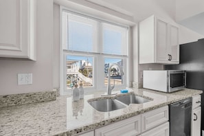 A kitchen with a double sink, a microwave, and white cabinets.