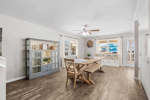 A dining area with a wooden table and chairs, a cabinet with glass doors, and a ceiling fan.