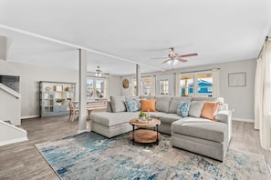 A living room with a sectional sofa, a coffee table, and a ceiling fan.