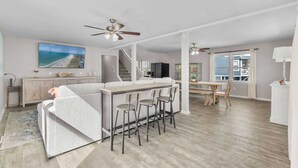 A spacious living area with a kitchen, dining space, and a large window. - Tides Like These (Murrells Inlet)