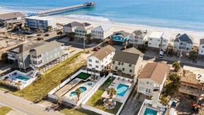 An aerial view of a coastal residential area with houses, a pier, and a beach. - Tides Like These (Murrells Inlet)