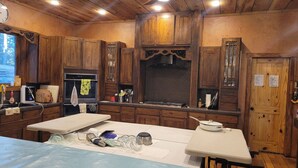 A kitchen with wooden cabinets, a stove, and a countertop with various kitchen items. - Woodland Haven: Private Mountain, Lodge on 21 Acres of Forest (Woodland Park)