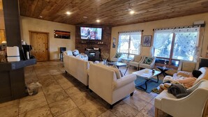 A cozy living room with a fireplace, comfortable seating, and a television. - Woodland Haven: Private Mountain, Lodge on 21 Acres of Forest (Woodland Park)