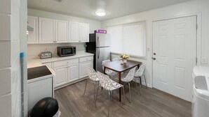 A compact kitchen with white cabinets, a refrigerator, a microwave, and a dining table with chairs. - Cozy 2BR/1BA Suite in a Quiet Renton Area (Renton)