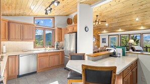 Eine moderne Küche mit Holzausstattung, einem Edelstahlkühlschrank und einer großen Kochinsel mit Barhocker.