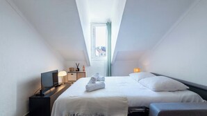 A modern, well-lit room with a bed, bedside table, lamp, and a view through a skylight. - Top Floor Studio – Heart of Cannes (Cannes)