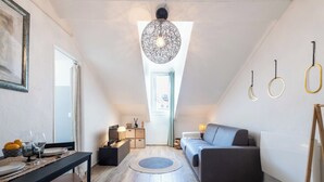 A modern loft bedroom with a dining area, a gray sofa, and a unique ceiling light fixture. - Top Floor Studio – Heart of Cannes (Cannes)