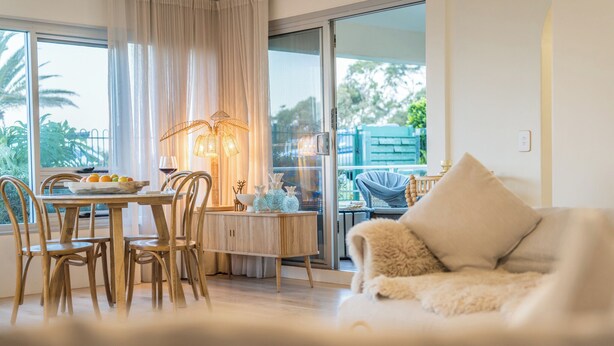 Ein gemütliches Wohnzimmer mit Essbereich, einer Couch und einem Balkon mit Blick auf Grünflächen.