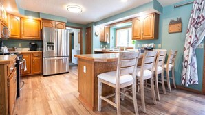 A modern kitchen with wooden cabinets, stainless steel appliances, and a central island with chairs. - Princeton View 3BR w/perfect backyard for dogs (Buena Vista)