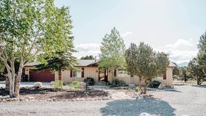 A single-story house with a red garage, surrounded by a gravel driveway and a stone border. - Princeton View 3BR w/perfect backyard for dogs (Buena Vista)