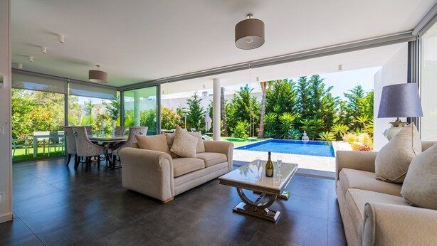 Una sala de estar moderna con piscina, ventanas amplias y zona de comedor.