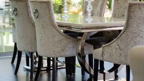 Un comedor con una mesa de vidrio, seis sillas y una vela.