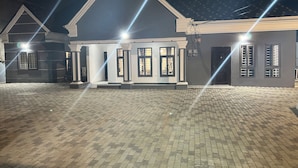 A building with a symmetrical facade, large windows, and a paved entrance area. - 1BR Ultra Modern House in Gbawe (Accra)