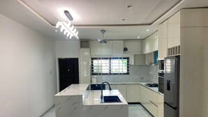 A modern kitchen with a central island, built-in appliances, and a ceiling fan. - 1BR Ultra Modern House in Gbawe (Accra)