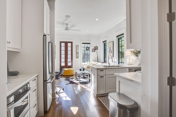 A modern kitchen with white cabinetry, a built-in oven, and a large island with a sink.