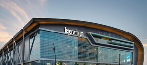 En moderne bygning med en buet facade og teksten 'Fiserv Forum' foran.