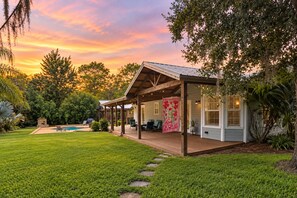 A house with a covered patio, a swimming pool, and a well-maintained lawn.