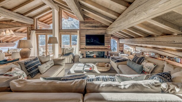 A cozy log cabin interior with a fireplace, comfortable seating, and large windows offering a view of the outdoors. - Luxury Catered Ski Chalet Blackcomb in Val d'Isere, France LVDI-4 (Val d'Isere)
