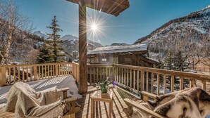 A wooden deck with a bench and a table, a dog, and a snowy mountain backdrop. - Luxury Catered Ski Chalet Blackcomb in Val d'Isere, France LVDI-4 (Val d'Isere)