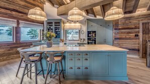 A kitchen with a large island, wooden ceiling beams, and pendant lights. - Luxury Catered Ski Chalet Blackcomb in Val d'Isere, France LVDI-4 (Val d'Isere)