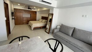 A compact bedroom with a bed, a sofa, a dining table, and a ceiling fan. - Beautiful beachfront condo, 5 min walk from downtown, (Cruz de Huanacaxtle)