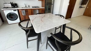 A compact kitchen with a built-in washing machine, a stainless steel refrigerator, and a dining table with four chairs. - Beautiful beachfront condo, 5 min walk from downtown, (Cruz de Huanacaxtle)