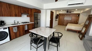 A compact kitchen with a dining area, a washing machine, and a bed in the adjacent room. - Beautiful beachfront condo, 5 min walk from downtown, (Cruz de Huanacaxtle)