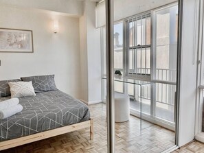A bedroom with a bed, a large window, and a view of the outside. - 83 OSHR (Bondi Junction)