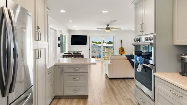 A modern kitchen with white cabinets, stainless steel appliances, and a large island. - Open Water Views, NEW Pool, Elevator & Easy Boating from Modern Canal Home (Cudjoe Key)