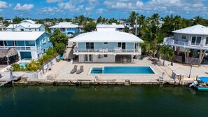 A coastal property with a swimming pool, a covered deck, and a view of the sea.