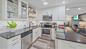 A modern kitchen with white cabinets, stainless steel appliances, and a granite countertop.