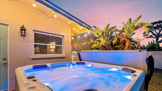 Un bain à remous en plein air, avec une maison en arrière-plan.