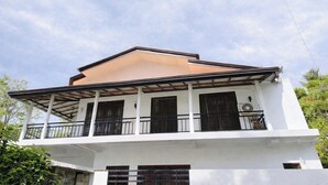 A two-story house with a balcony, white exterior walls, and a brown roof. - Yala Quest Safaris/Tours/HomeStay - Tissamaharama (Mahasenpura, Tissamaharama)