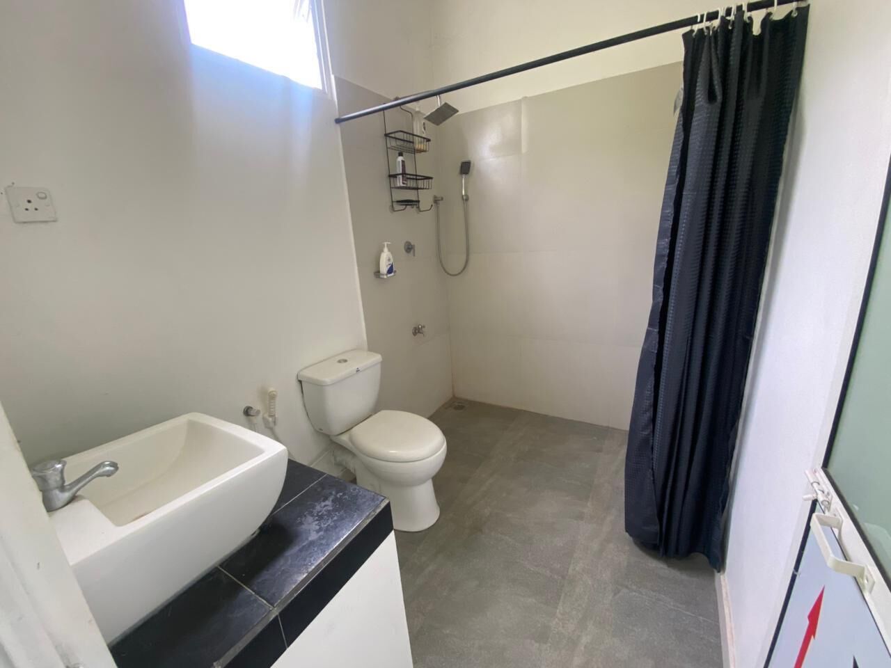 Un bagno con lavandino, WC e doccia bianchi.