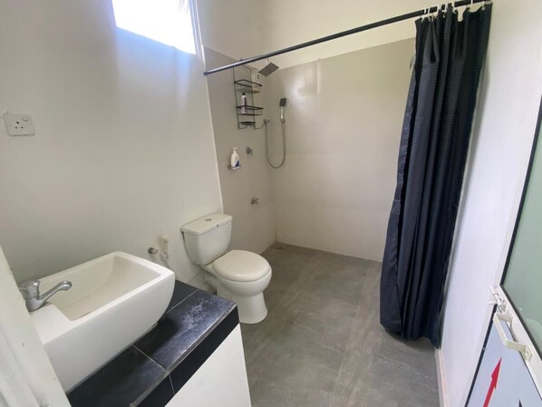 A bathroom with a white sink, toilet, and shower.